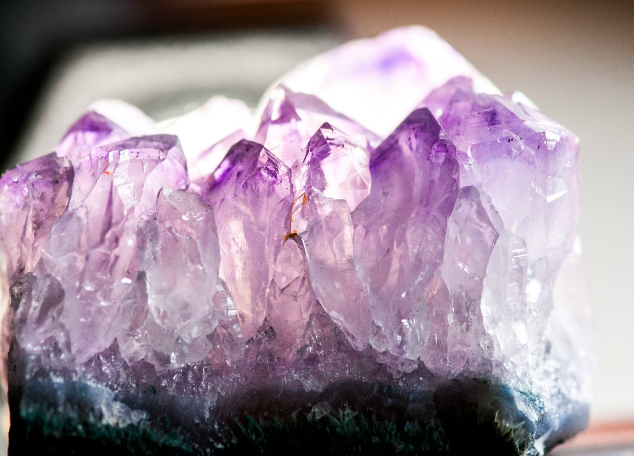 Close-up of an amethyst crystal cluster with pointed, transparent purple and lilac tips—like a true Jewel in the Desert—showing intricate natural formations and a gradient of color from deep violet to pale lavender.